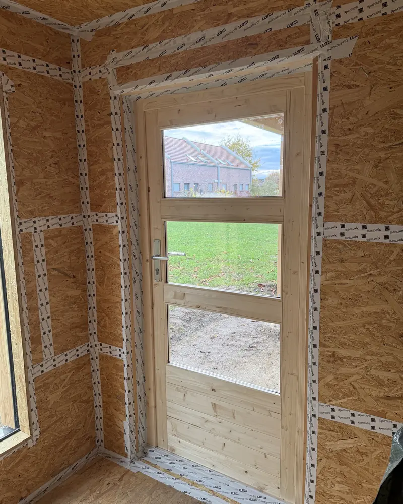 Eingesetzte Holztür mit Glasfeld in einem mit OSB beplankten Gartenhaus