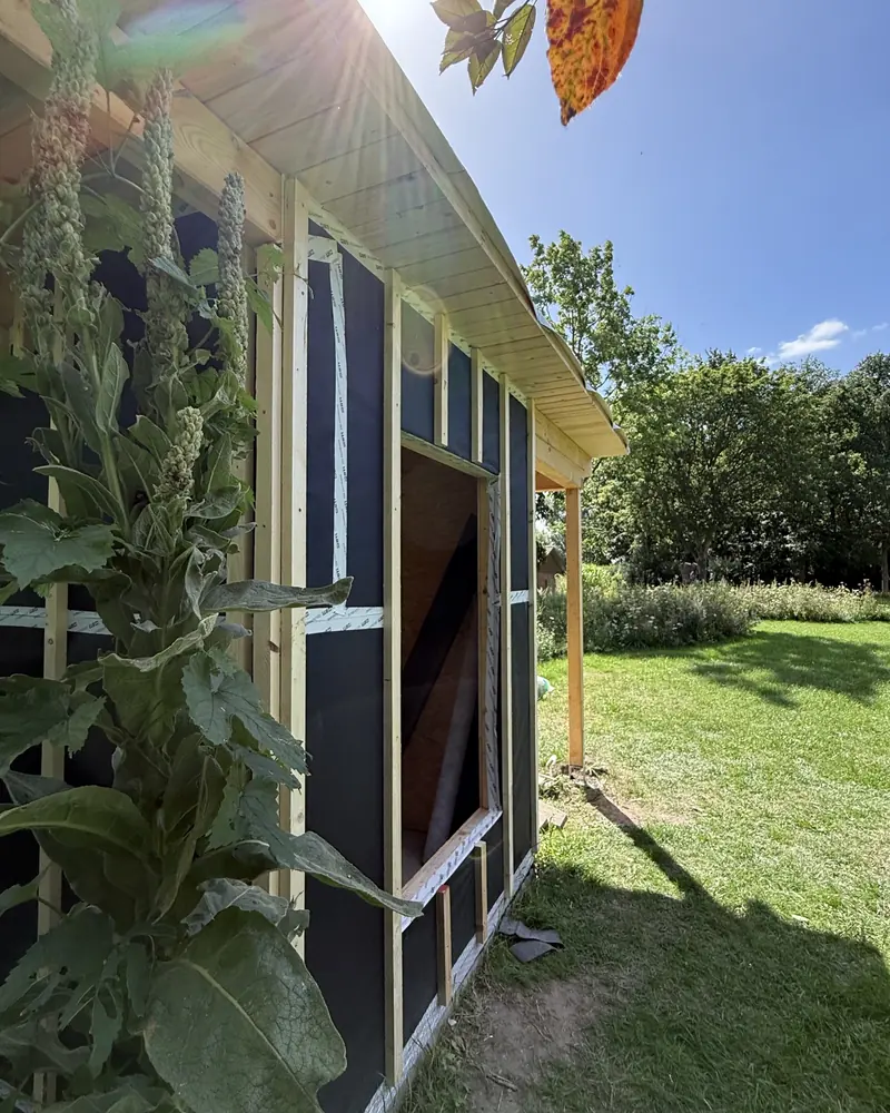 Gartenhaus mit Lattung für die Fassadenschalung im Gegenlicht der Sommersonne