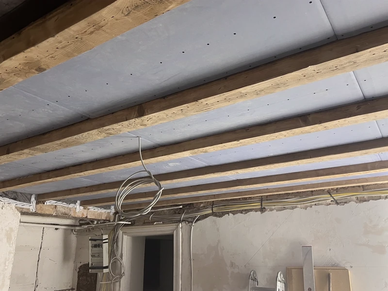 Deckenverkleidung mit Platten zwischen freigelegten Holzbalken
