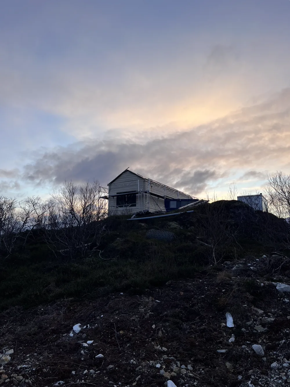Silhouette des im Rohbau befindlichen Hauses auf einem Hügel bei Dämmerung