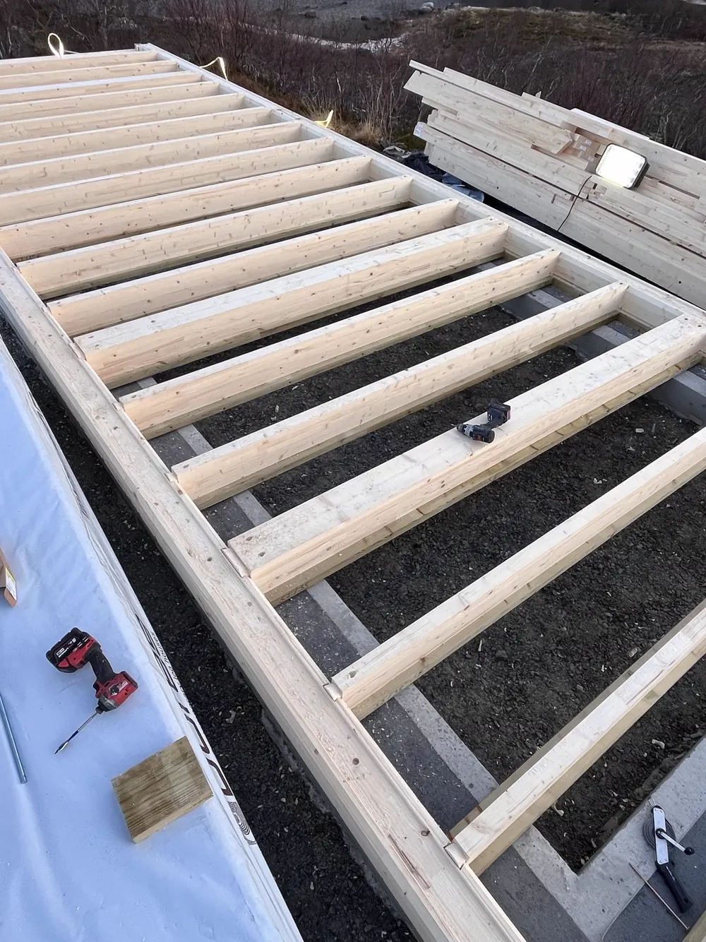 Verlegte Bodenbalken auf dem Fundament mit Werkzeug auf der Baustelle